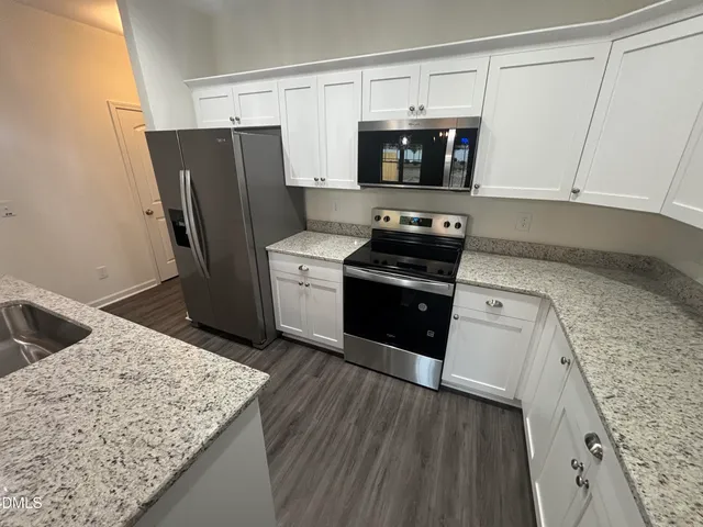 a kitchen with stainless steel appliances granite countertop a stove a sink and a microwave