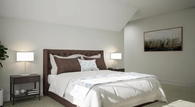 a bedroom with a bed and a lamp on dresser