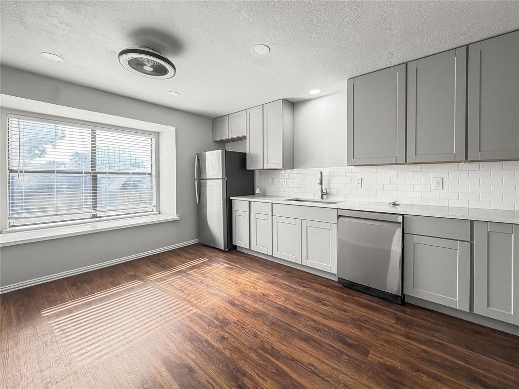 5840 Spring Valley Road, Unit 1104 Dallas, TX 75254 - Photo 13 of 16 Kitchen space featuring wood-finish flooring, light gray cabinetry, white subway tile backsplash, and stainless steel appliances