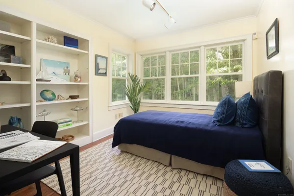 a bedroom with a bed a table and a large window
