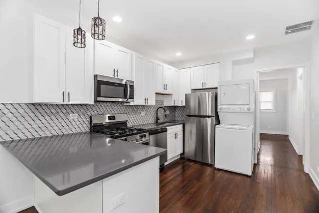 a kitchen with a refrigerator a stove top oven a sink dishwasher a dining table and chairs with wooden floor