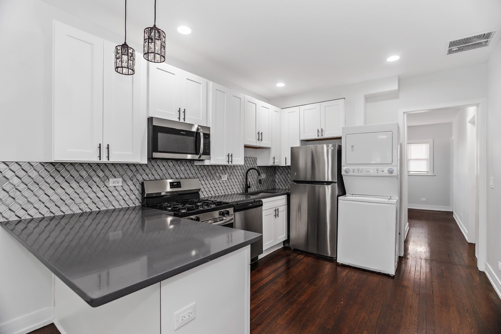 4313 West Parker Avenue Chicago, IL 60639 - Photo 5 of 17 a kitchen with a refrigerator a stove top oven a sink dishwasher a dining table and chairs with wooden floor