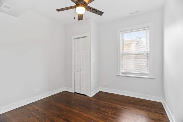 an empty room with wooden floor fan and windows