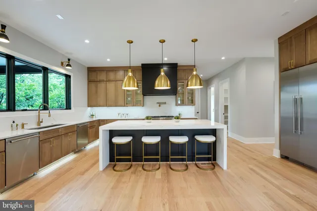 a large kitchen with stainless steel appliances a large counter top a stove a sink and a refrigerator