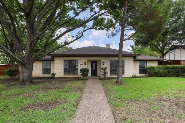 a front view of a house with a garden and trees