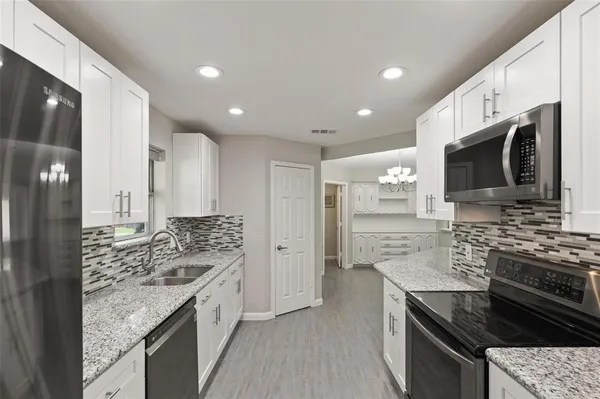 a kitchen with stainless steel appliances granite countertop a stove top oven a sink dishwasher a refrigerator and a oven with wooden floor