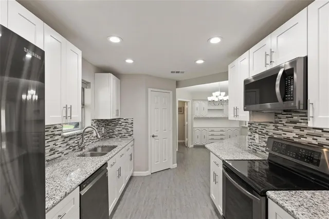 a kitchen with stainless steel appliances granite countertop a stove top oven a sink dishwasher a refrigerator and a oven with wooden floor