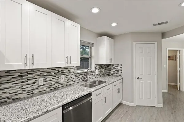 a kitchen with granite countertop white cabinets and sink