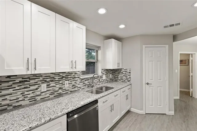 a kitchen with granite countertop white cabinets and sink