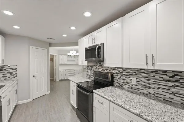 a kitchen with stainless steel appliances granite countertop a stove a sink and a microwave