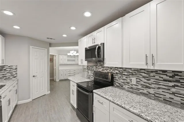 a kitchen with stainless steel appliances granite countertop a stove a sink and a microwave