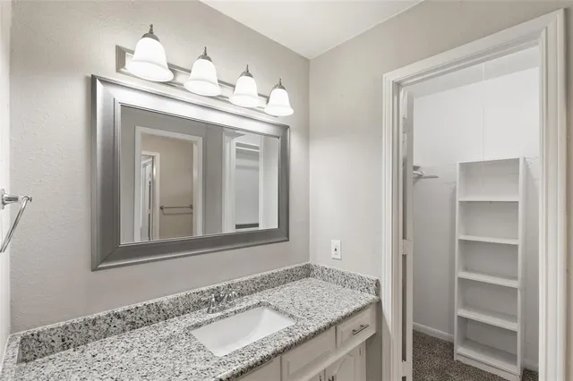 a bathroom with a granite countertop sink and a window