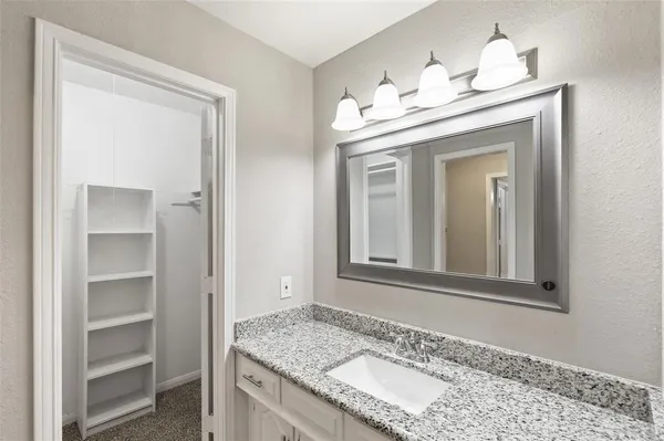a bathroom with a granite countertop sink and a mirror