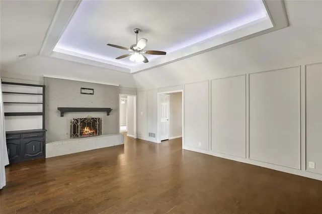a view of an empty room with a fireplace and a ceiling fan