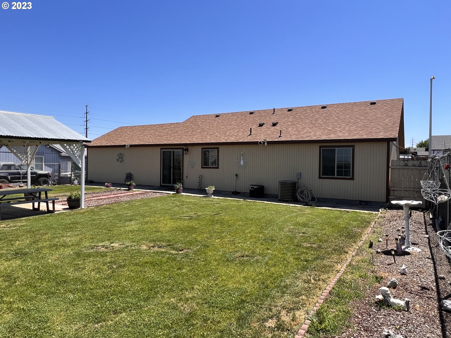 155 Pine Tree Avenue Umatilla, OR 97882 - Photo 14 of 15 a backyard of a house with table and chairs under an umbrella