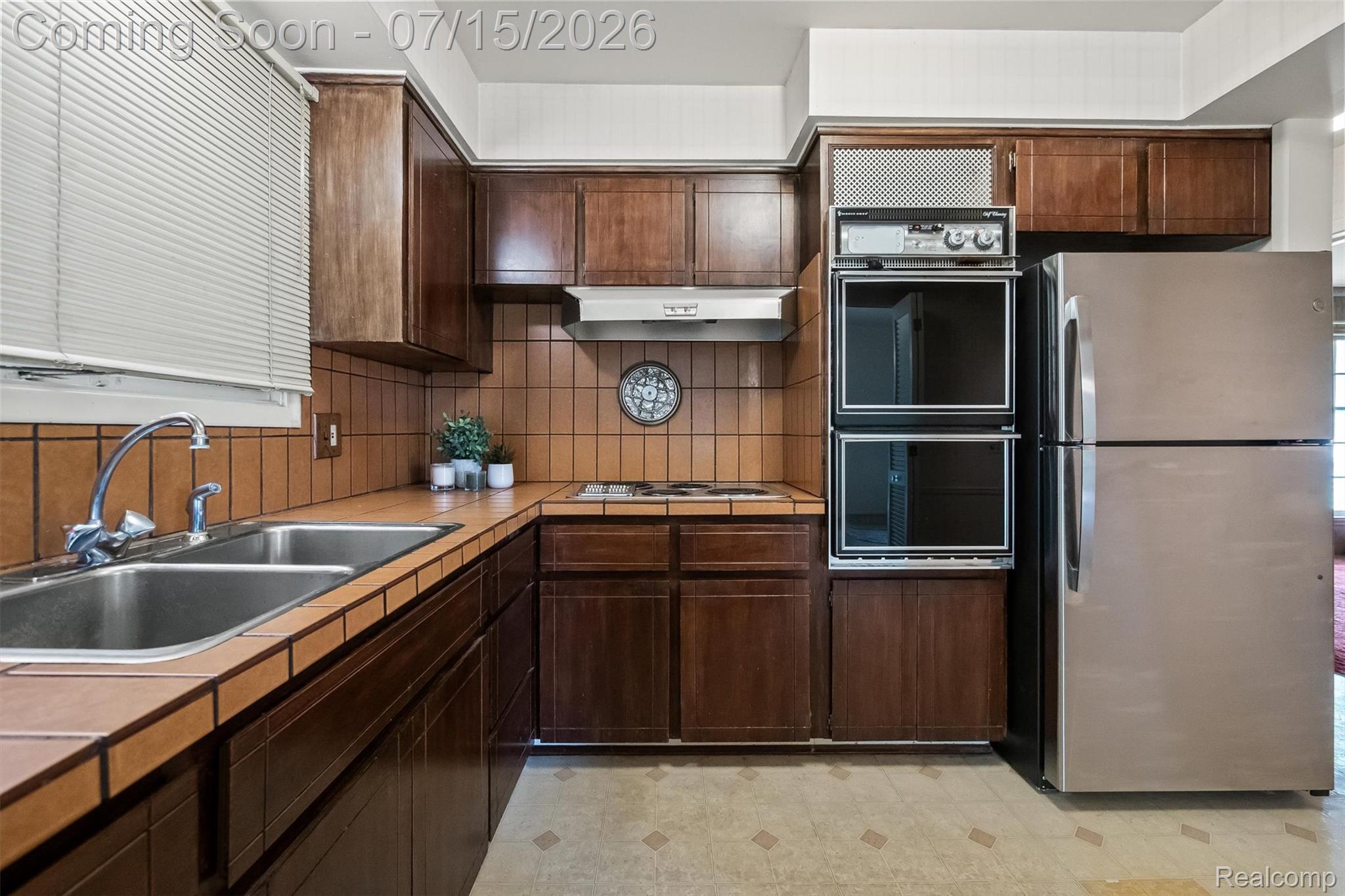 1151 Peveril Road Bloomfield Hills, MI 48304 - Photo 14 of 39 Eat-in kitchen featuring dark wood cabinetry, a double basin stainless steel sink, and tiled countertops