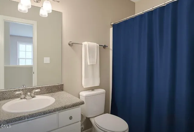 a bathroom with a granite countertop sink toilet and a mirror