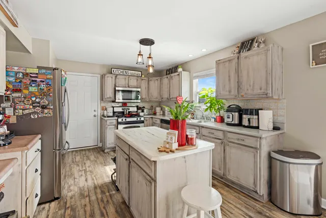 a kitchen with kitchen island granite countertop a sink refrigerator and cabinets
