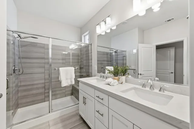 a bathroom with a double vanity sink mirror and shower