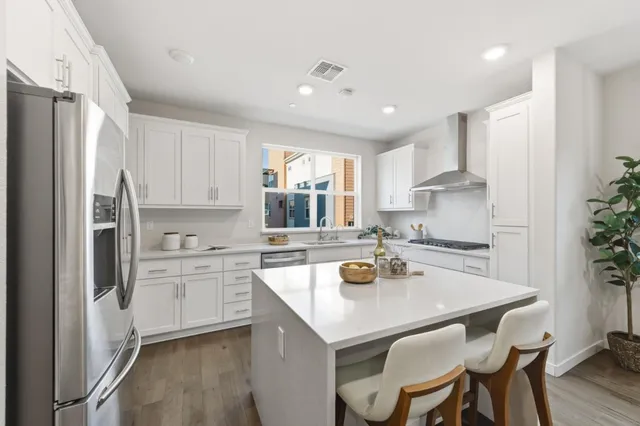 a kitchen with a refrigerator a stove a sink a dining table and chairs