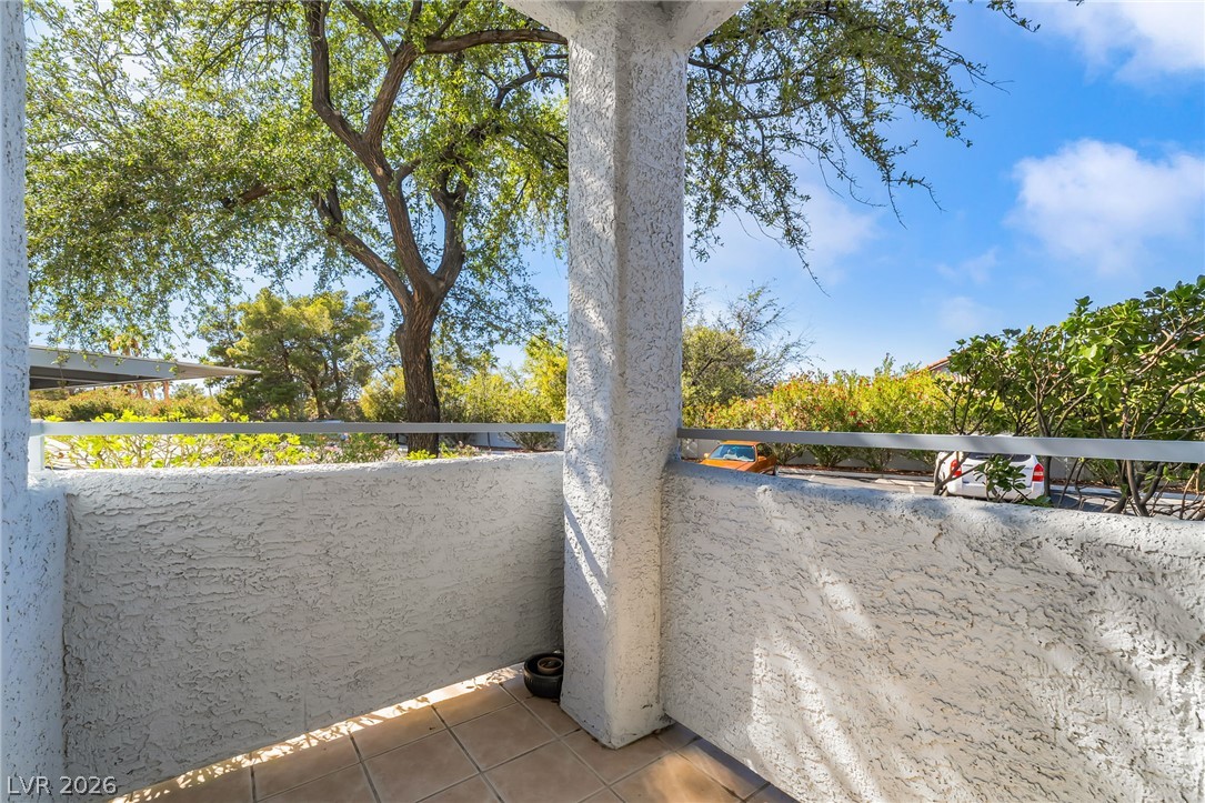 2201 Ramsgate Drive, Unit 811 Henderson, NV 89074 - Photo 29 of 36 A tiled balcony offers a serene outdoor space, perfect for quiet contemplation amidst verdant surroundings.