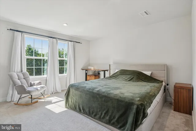 a bed sitting in a spacious bedroom next to a window and work place
