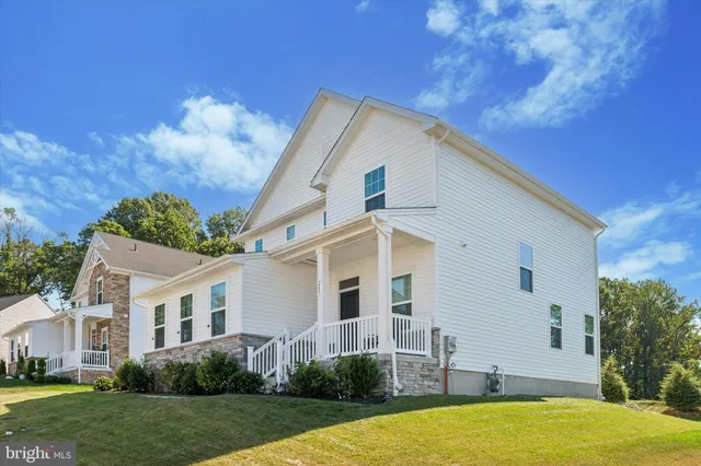 a view of a white house next to a yard with plants and trees