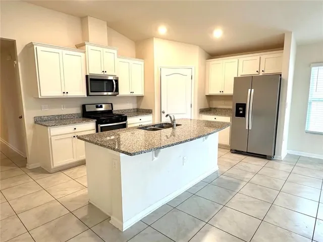 a kitchen with stainless steel appliances granite countertop a sink a stove a microwave a refrigerator a counter top space and cabinets