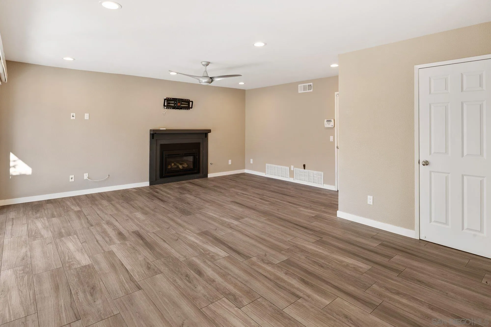 14274 Woodcreek Road Poway, CA 92064 - Photo 18 of 57 an empty room with wooden floor fireplace and windows