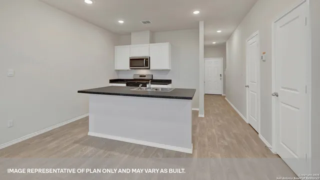 a kitchen with kitchen island sink stove and white cabinets