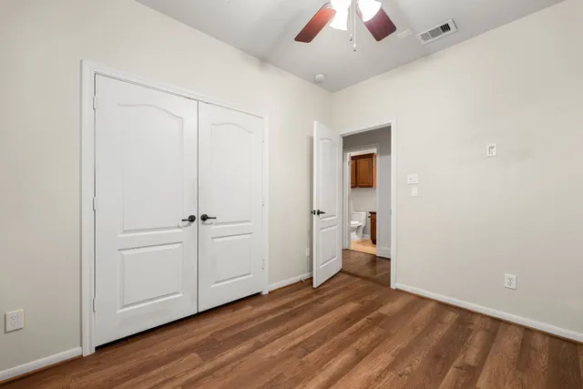 an empty room with wooden floor closet and windows