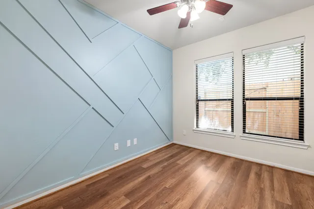 a view of empty room with wooden floor and fan