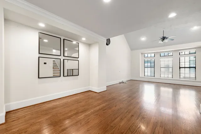 a view of an empty room with window and wooden floor