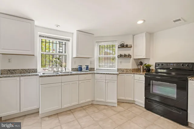 a kitchen with granite countertop white cabinets and appliances