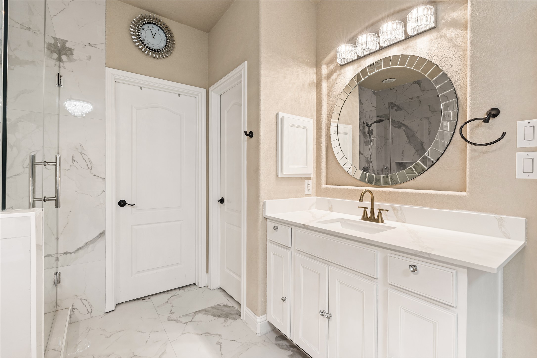 5802 Layton Meadows Lane Spring, TX 77379 - Photo 23 of 42 Master bathroom second angle. Shows the other vanity, gold hardware, round tiled mirror, crystal sconces, marble floors, and glass shower entry. Confirms the full spa experience.
