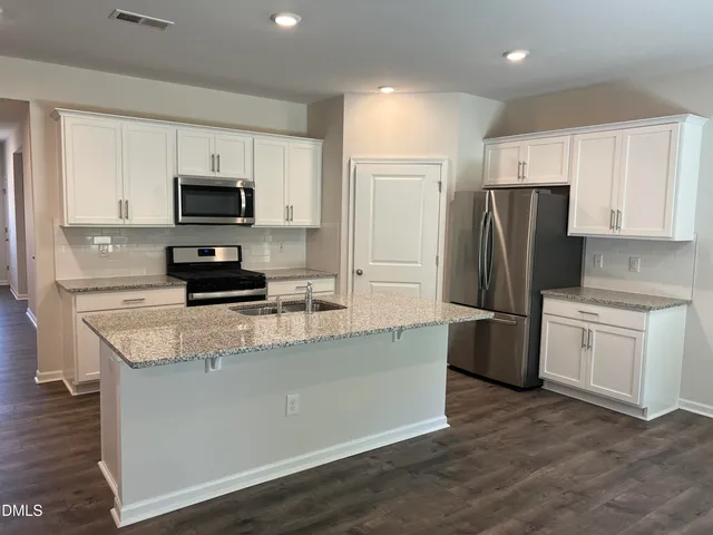 a kitchen with kitchen island a white cabinets and refrigerator