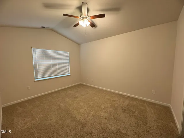 an empty room with a chandelier fan and windows