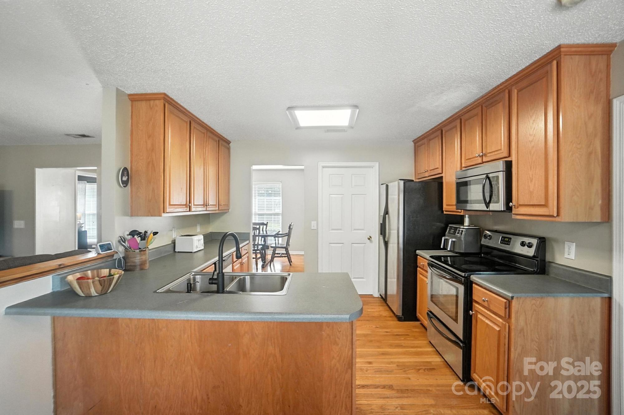 1116 State Rd S-29-770 Kershaw, SC 29067 - Photo 12 of 48 a kitchen with stainless steel appliances granite countertop a refrigerator a stove a sink dishwasher and wooden cabinets with wooden floor