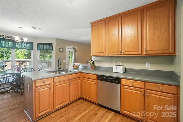 a kitchen with stainless steel appliances granite countertop wooden cabinets a sink and dishwasher with wooden floor