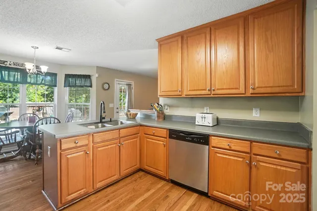 a kitchen with stainless steel appliances granite countertop wooden cabinets a sink and dishwasher with wooden floor