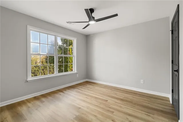 a view of an empty room with wooden floor and a window