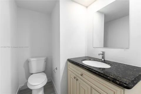 a bathroom with a granite countertop sink a toilet and a mirror