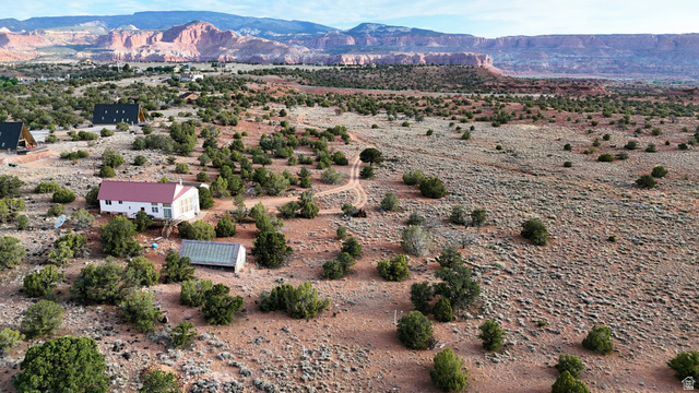 358 South Sky Drive Torrey, UT 84775 - Photo 1 of 82 Sprawling high desert landscape featuring a central white residence with a red roof, a secondary structure, and two A-frame cabins amidst natural vegetation