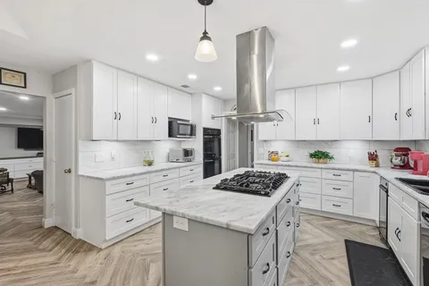 a kitchen with stainless steel appliances kitchen island granite countertop a sink stove and white cabinets