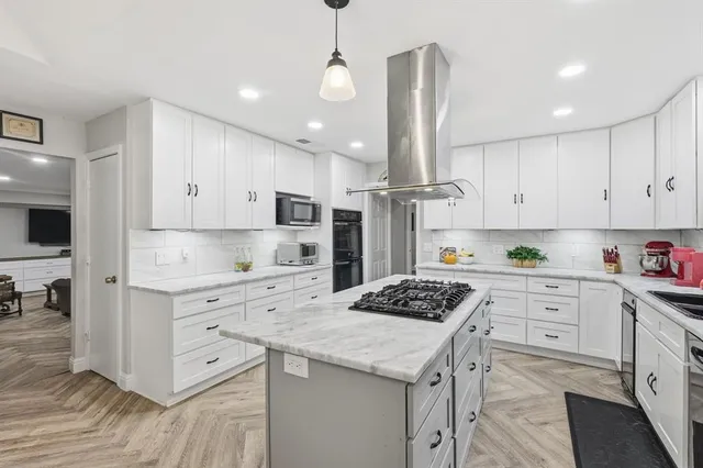 a kitchen with stainless steel appliances kitchen island granite countertop a sink stove and white cabinets