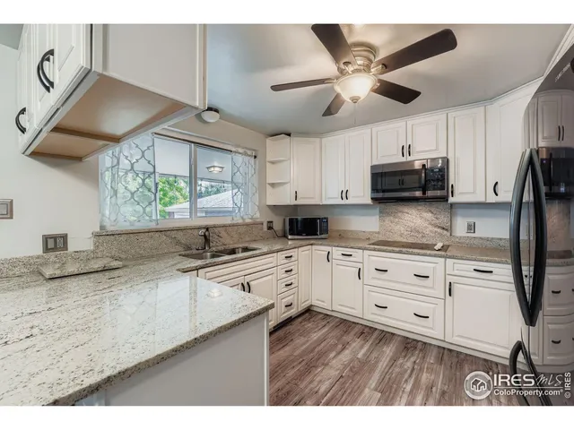 a kitchen with stainless steel appliances granite countertop a sink a stove a refrigerator a microwave oven with cabinets and wooden floor