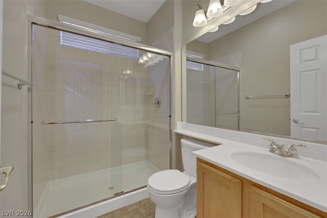 10328 Hawk Ravine Street Las Vegas, NV 89178 - Photo 19 of 55 A well-appointed bathroom features a glass-enclosed shower and a vanity with a large mirror, creating a practical and inviting space.