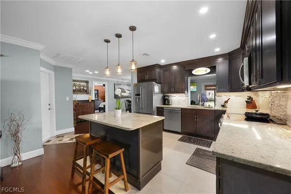 a kitchen with kitchen island granite countertop a sink a counter top space appliances and cabinets