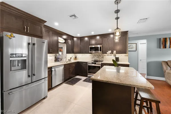 a kitchen with refrigerator a island and chairs