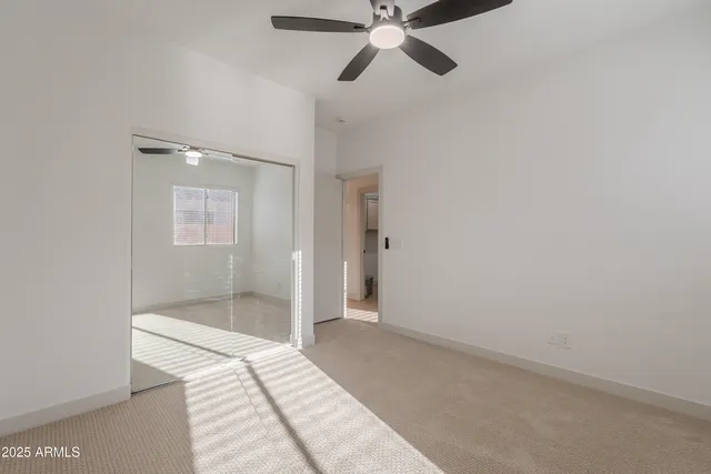 a view of empty room with window and ceiling fan